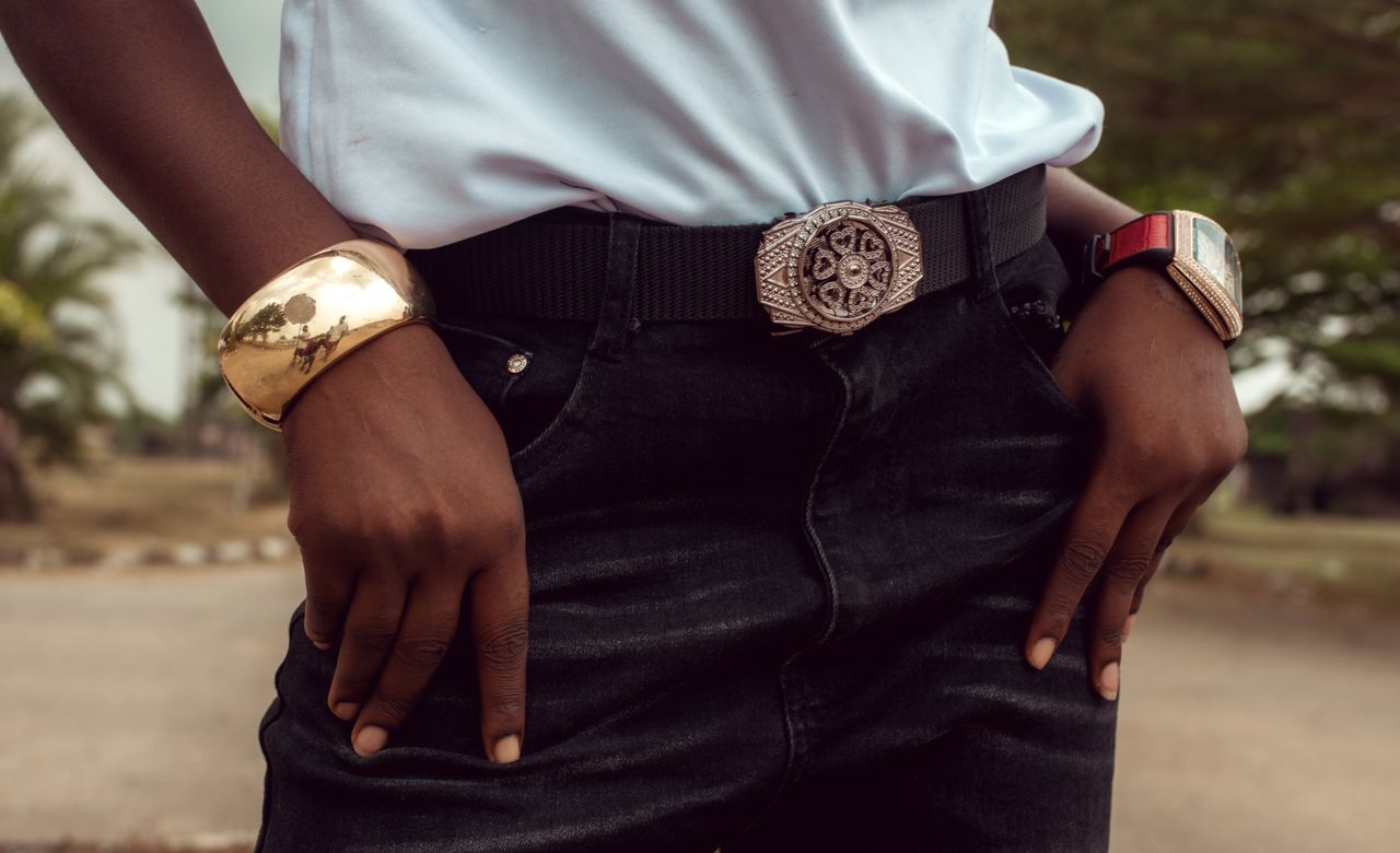 Young adult showcasing fashion accessories with a focus on elegant jewelry and belt outdoors in Nigeria.